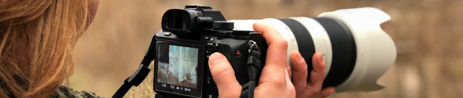 Kvinde holder systemkamera med 70-200 mm-objektiv